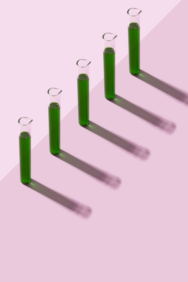 Row of test tubes with liquid, pink background